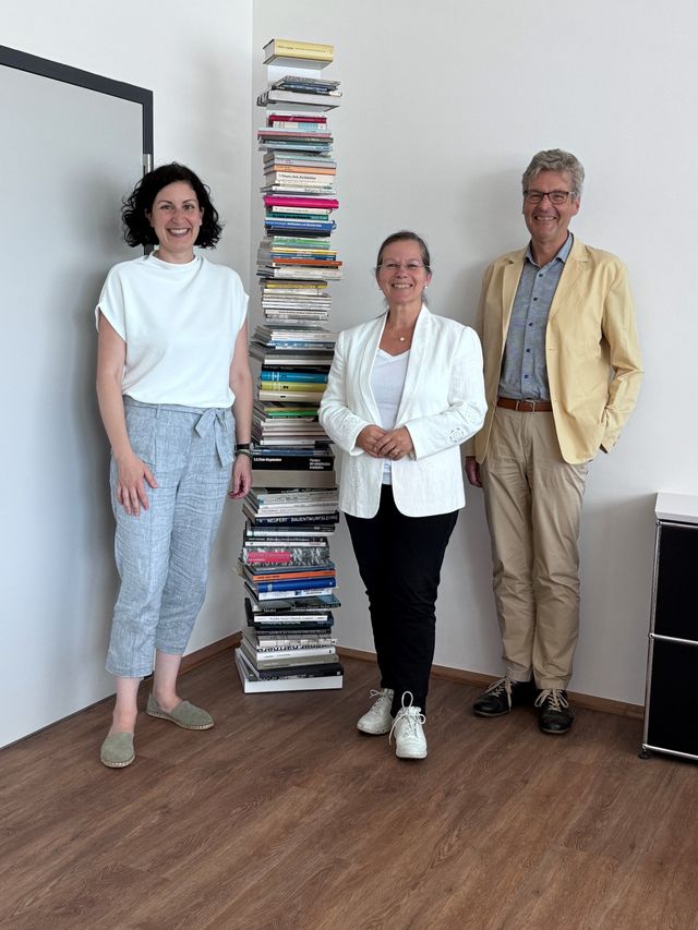 Sarah Hagmann, Diana Stöcker und Lorenz Wehrle vor einem vertikalen Bücherregal im Amtszimmer in Weiler Rathaus